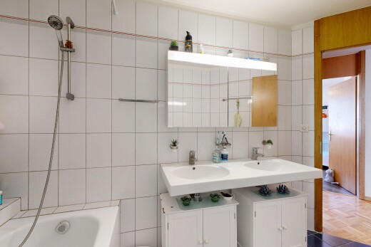 bathroom with tile walls, double vanity, and bathtub / shower combination