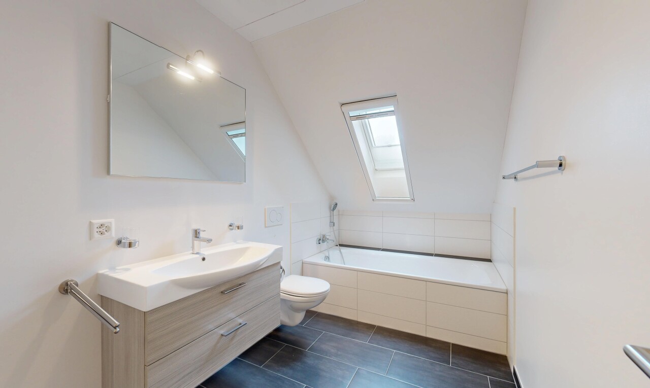 salle de bains avec puits de lumière, miroir, lavabo (ou coiffeuse selon le contexte), salle de bain complète, et bain