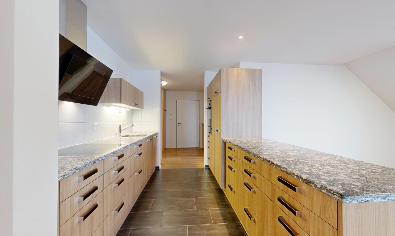 cuisine avec plans de travail en pierre, armoires marron clair, armoires à panneau plat, inside property, et drywall