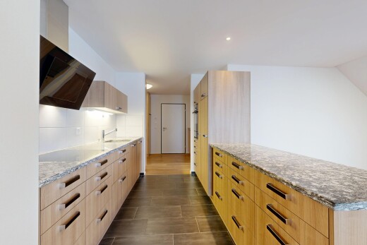 cuisine avec plans de travail en pierre, armoires marron clair, armoires à panneau plat, inside property, et drywall