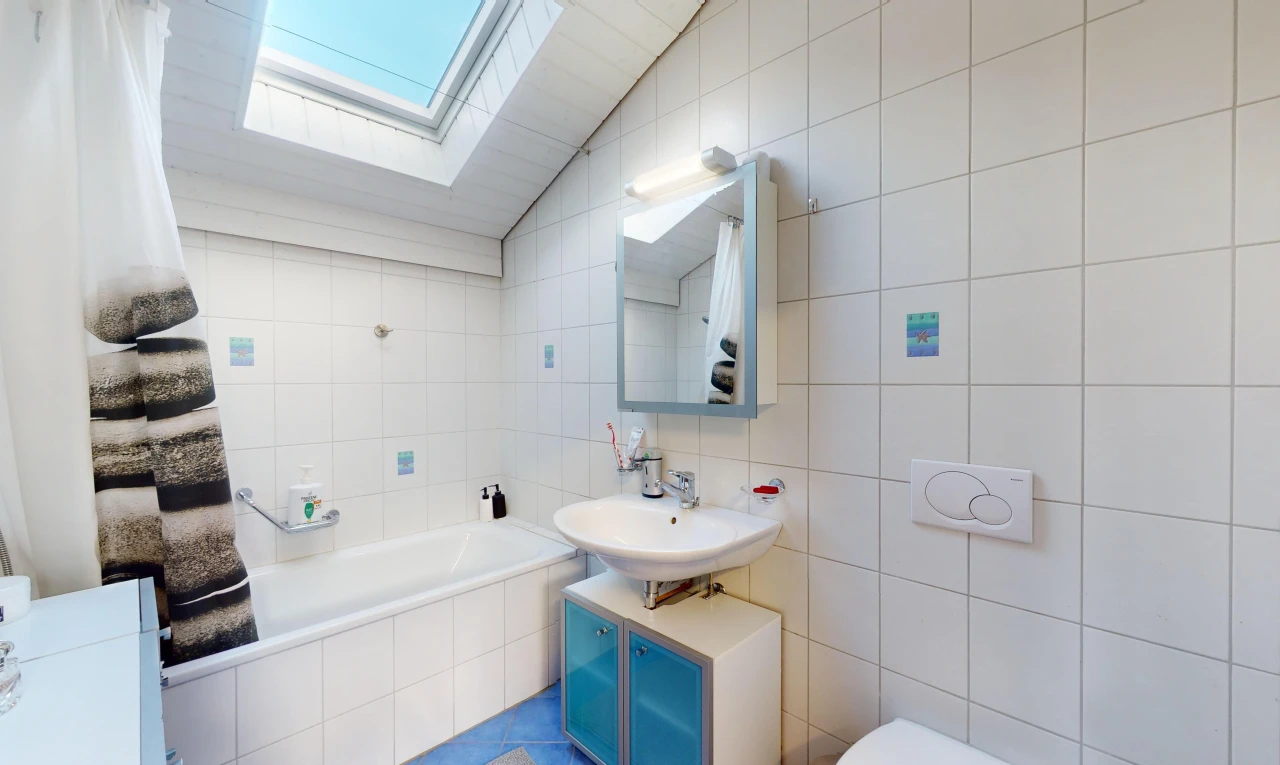 bathroom featuring vanity, tile walls, vaulted ceiling with skylight, and tiled tub