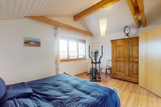 chambre avec poutres apparentes, lumière naturelle, plafond voûté, et plancher de bois