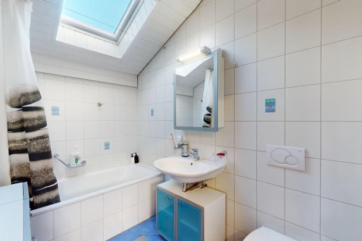 bathroom featuring vanity, tile walls, vaulted ceiling with skylight, and tiled tub
