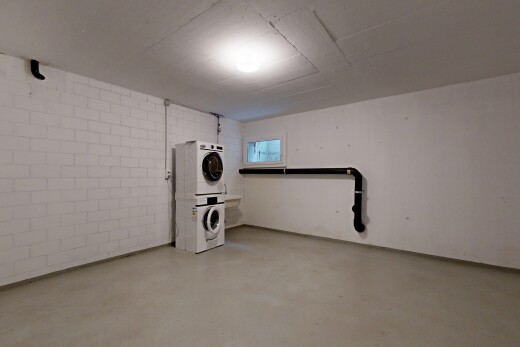 laundry area featuring stacked washer and clothes dryer, concrete floors, and concrete block wall
