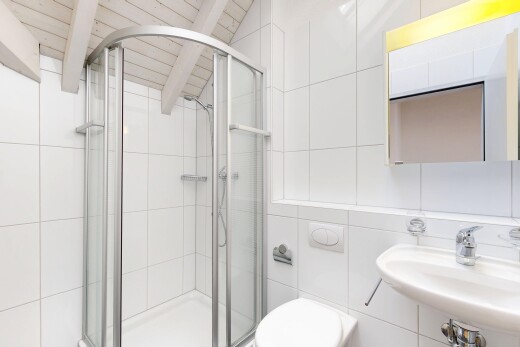full bathroom with tile walls, a stall shower, and beam ceiling
