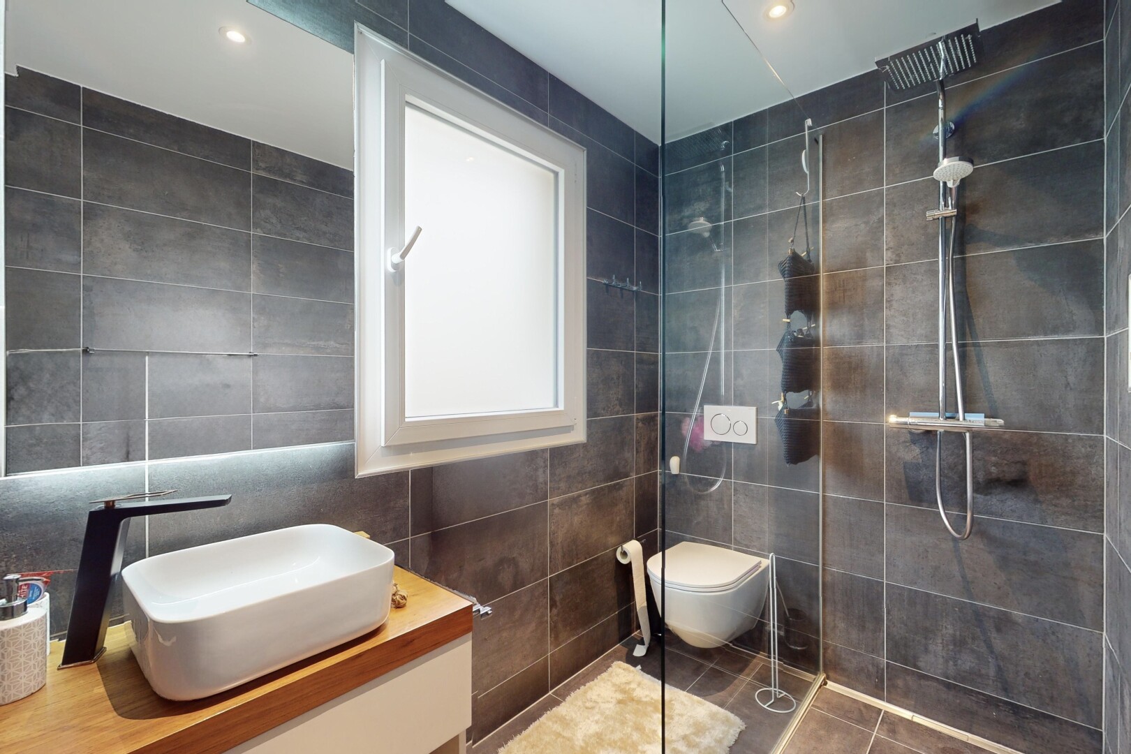salle de bains avec douche, carrelage, meuble-lavabo, et mur carrelé