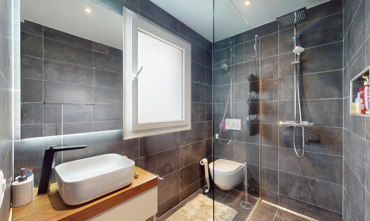salle de bains avec douche, carrelage, meuble-lavabo, et mur carrelé