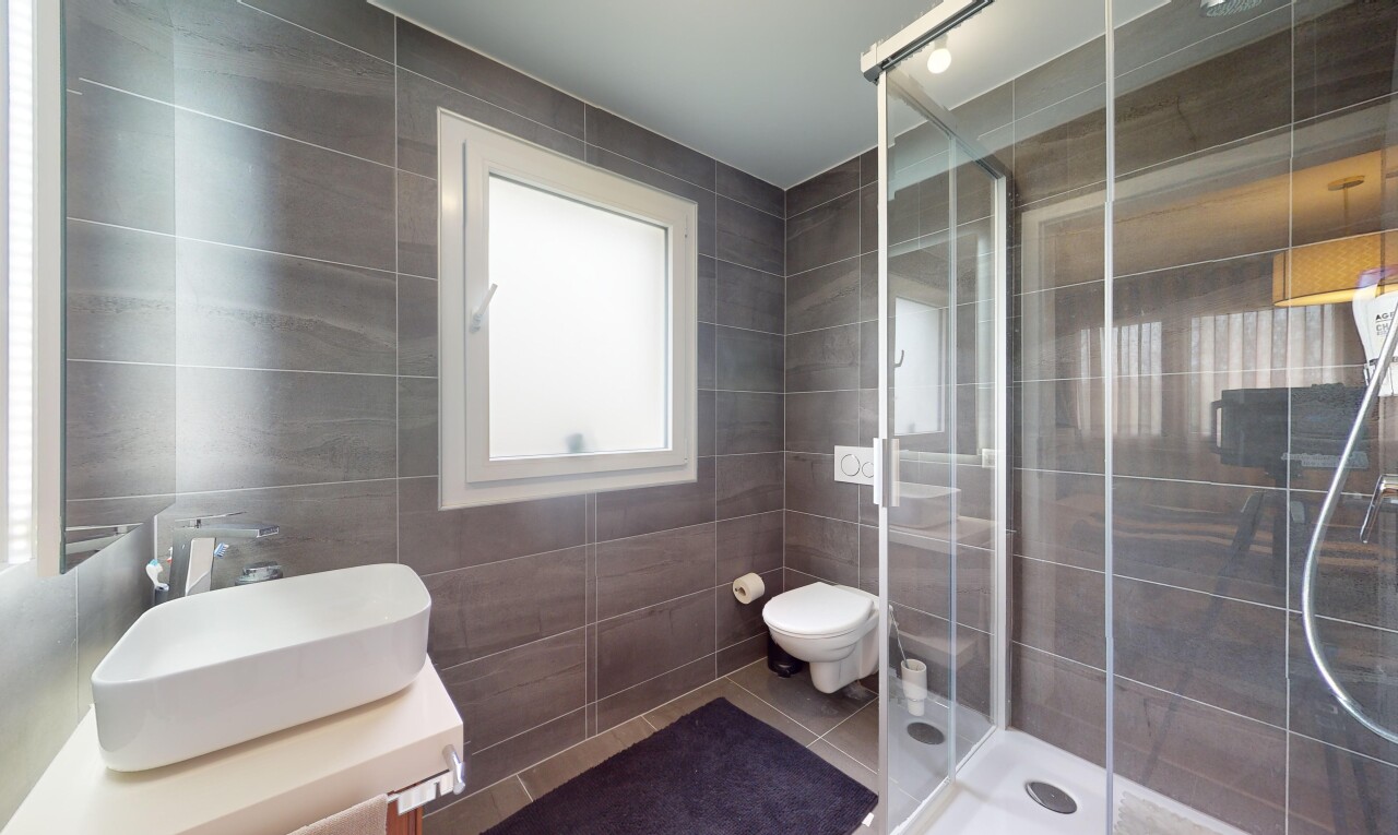 salle de bains avec mur carrelé, carrelage, lumière naturelle, et douche