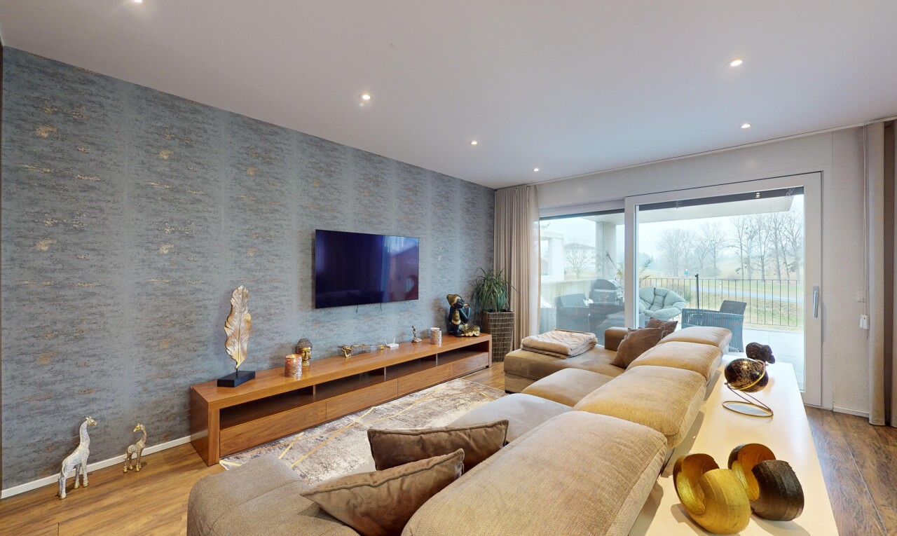 salon avec lumière naturelle, télévision, et plancher de bois
