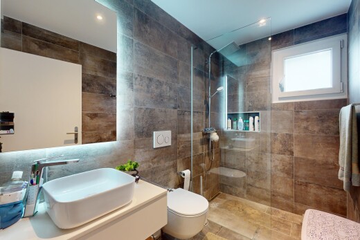salle de bains avec vasque, lumière naturelle, miroir, douche, et mur carrelé