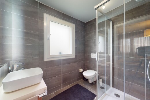 salle de bains avec mur carrelé, carrelage, lumière naturelle, et douche