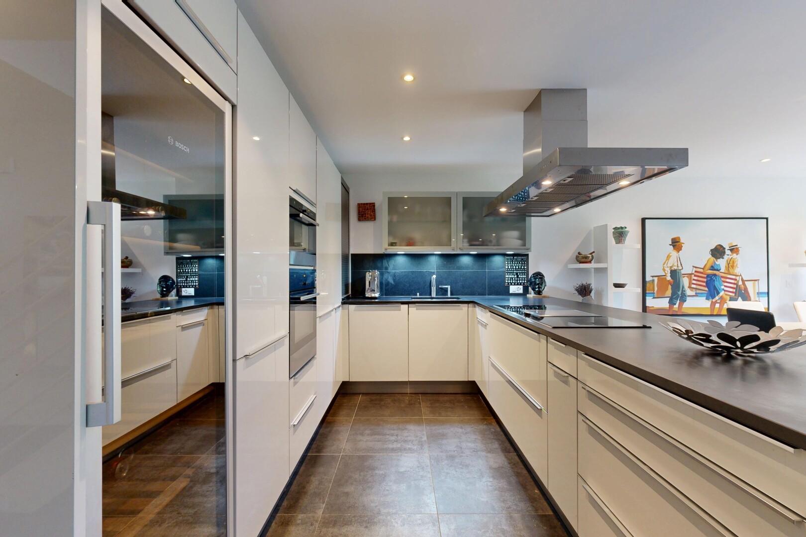 cuisine avec hotte, plans de travail, dark countertops, dark floor, et armoires avec insert en verre