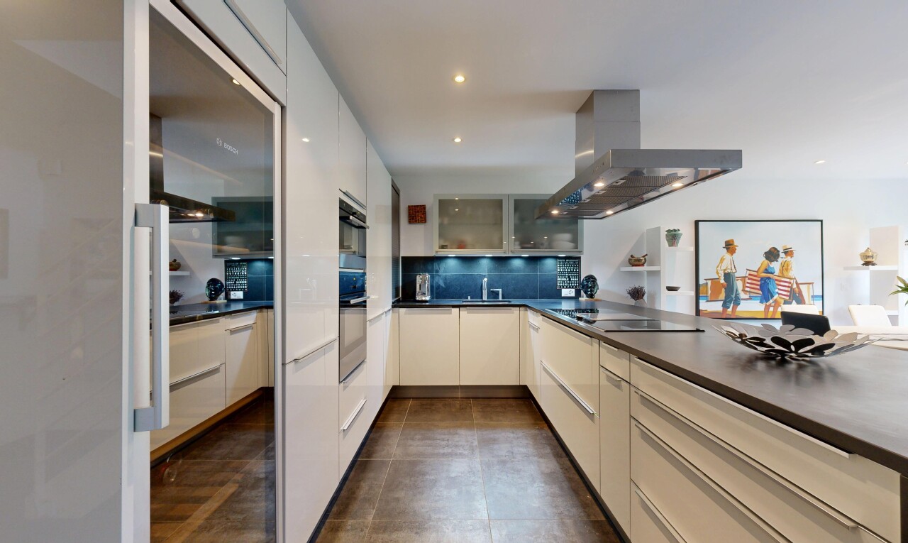 cuisine avec hotte, plans de travail, dark countertops, dark floor, et armoires avec insert en verre