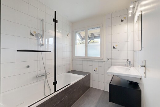 salle de bains avec mur en carrelage, tile wall, douche-bain combinés, inside property, et lumière naturelle