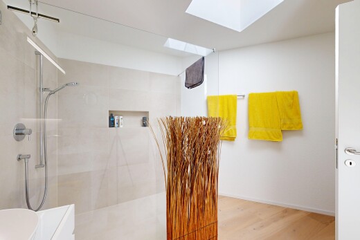 bathroom featuring walk in shower, a skylight, and light wood finished floors
