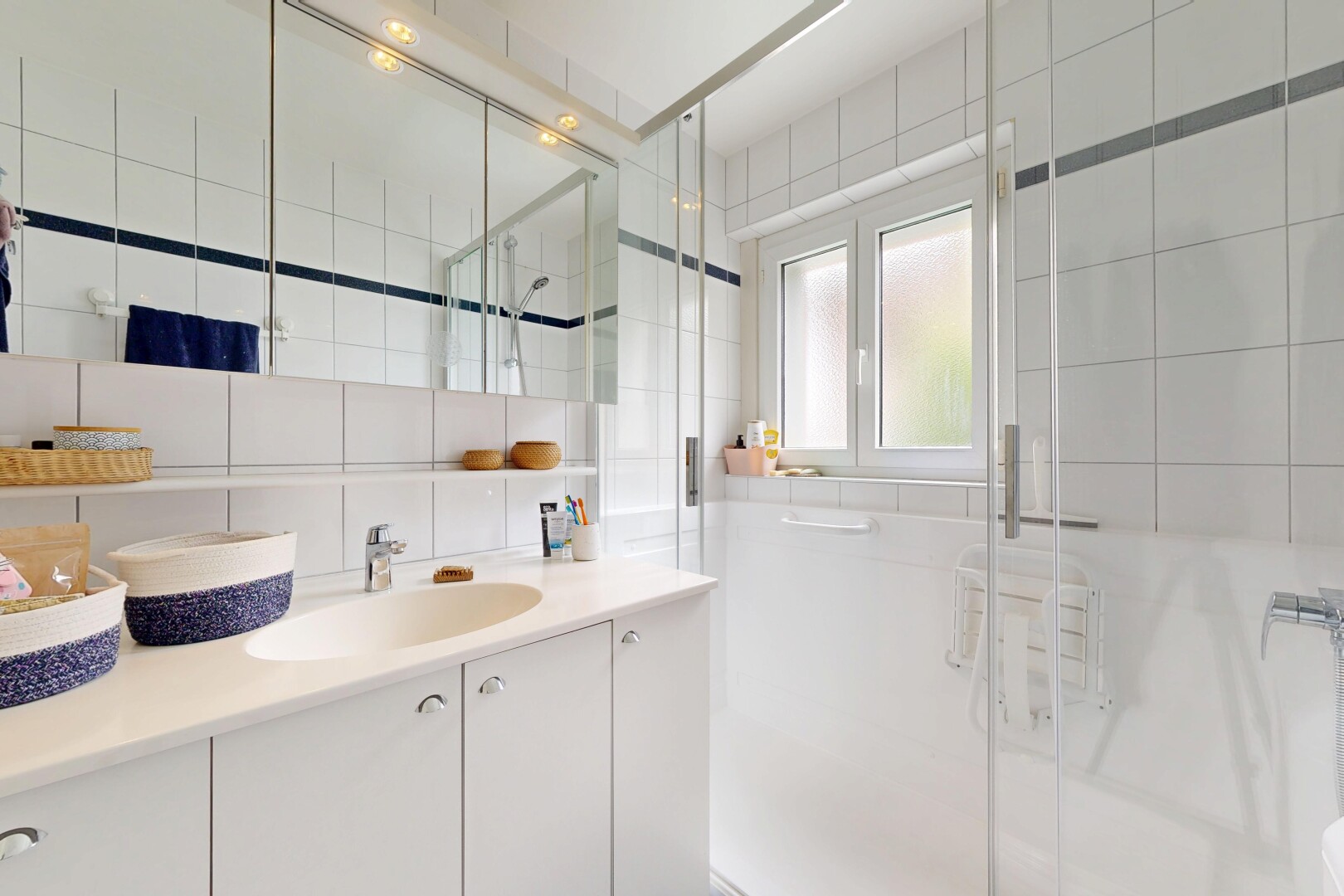 salle de bains avec mur en carrelage, tile wall, douche, lavabo (ou coiffeuse selon le contexte), et salle de bain complète