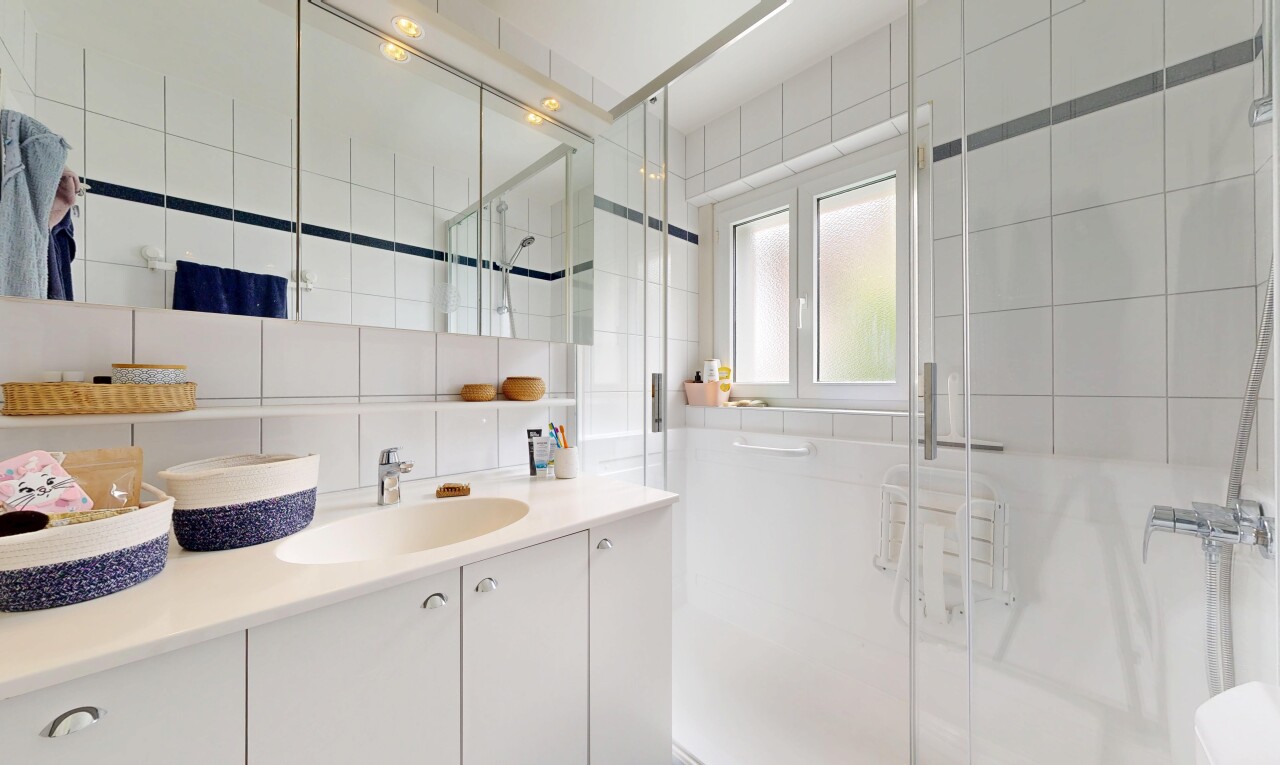 salle de bains avec mur en carrelage, tile wall, douche, lavabo (ou coiffeuse selon le contexte), et salle de bain complète