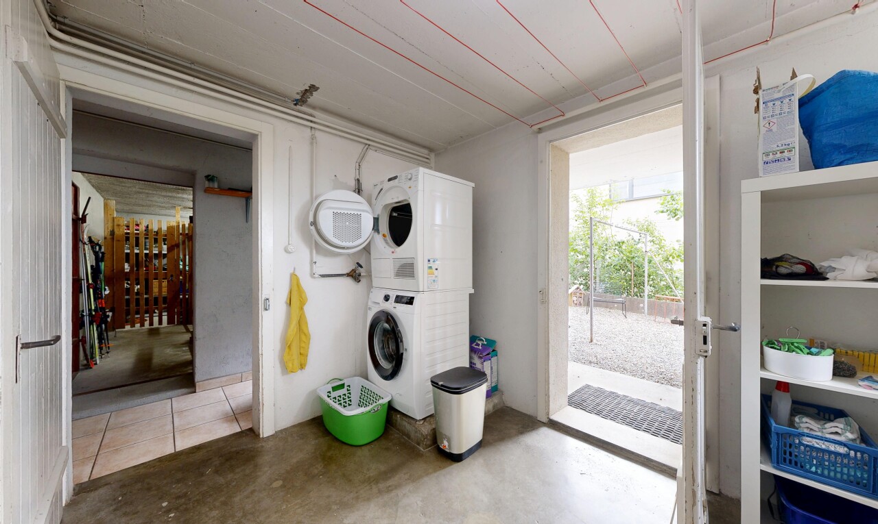buanderie avec lave-linge et sèche-linge superposés, sol en béton, concrete floor, inside property, et light floor