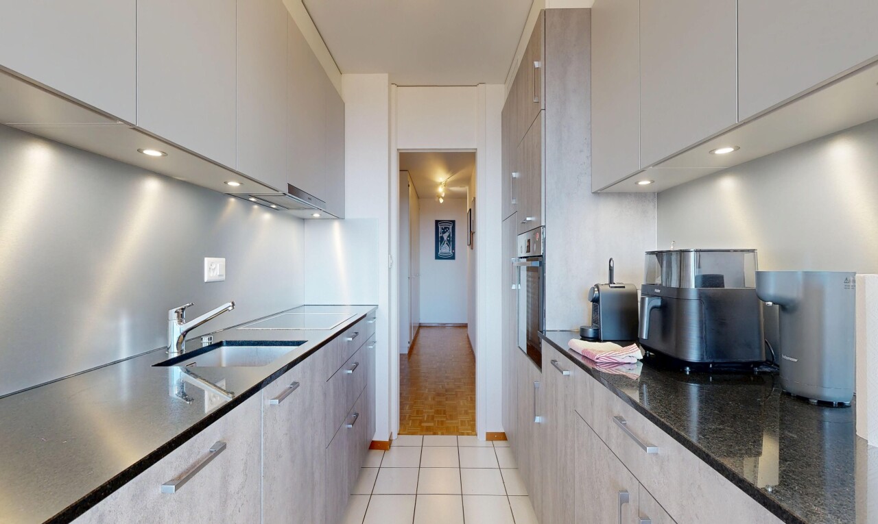 cuisine avec dark countertops, flat panel cabinets, armoires à panneau plat, light floor, et stone countertops