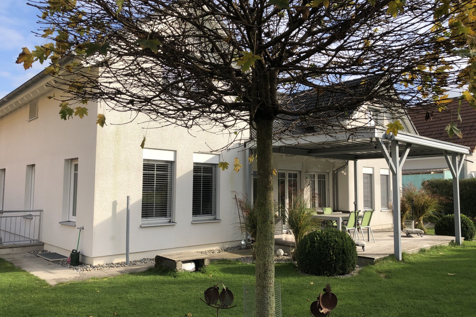 façade avec fondation en béton, bardage en stuc, property visible, terrasse, et pelouse