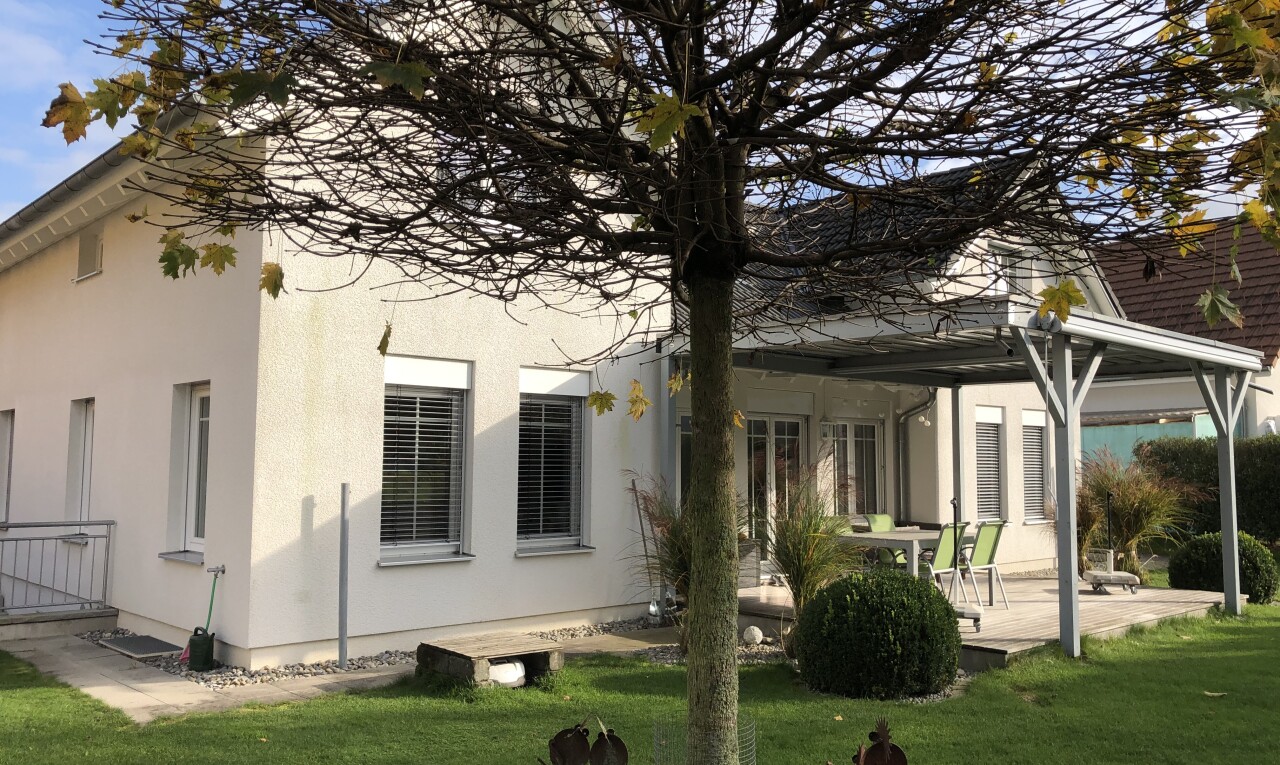 façade avec fondation en béton, bardage en stuc, property visible, terrasse, et pelouse