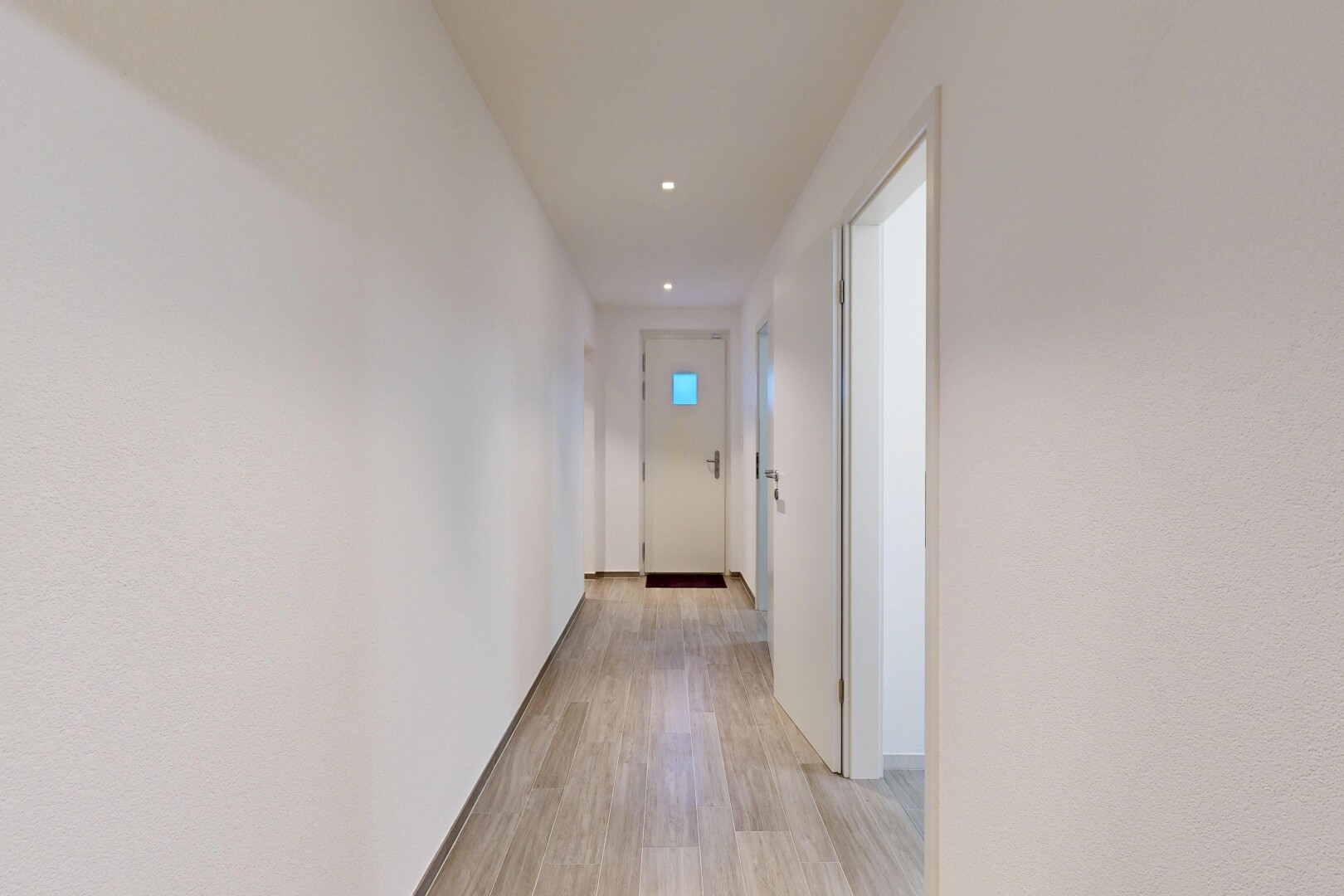 couloir avec wood finish floor, sol en finition bois, light floor, inside property, et recessed lighting