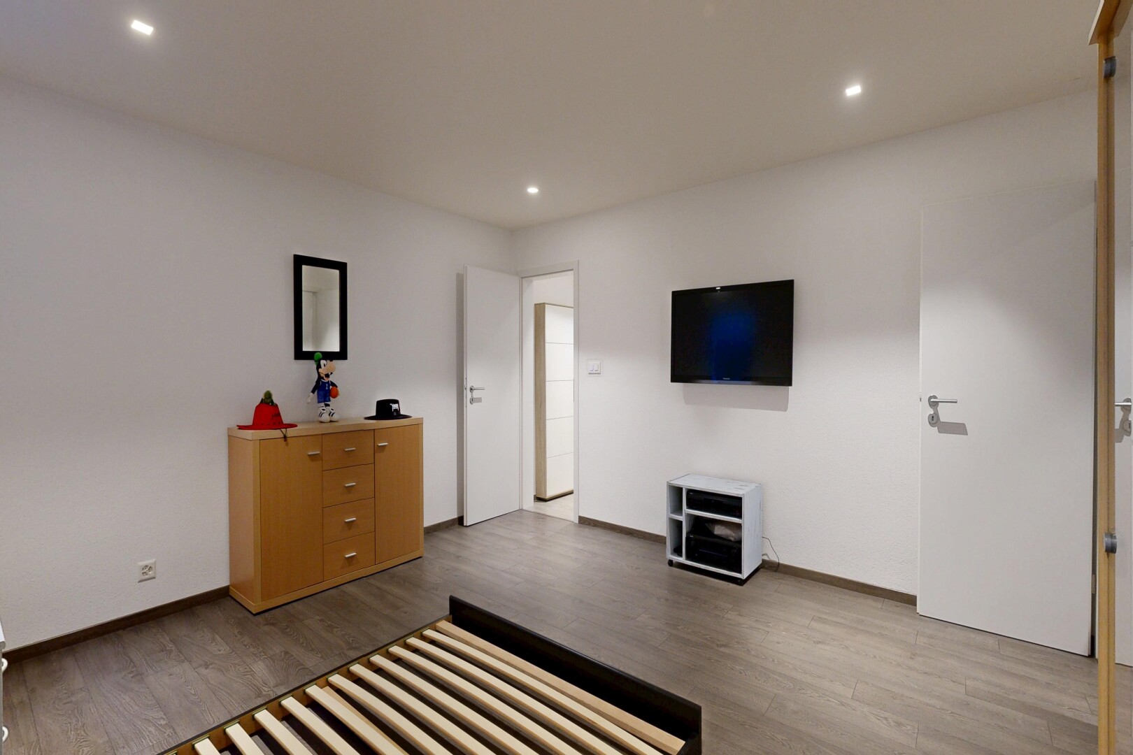 chambre avec télévision, sol en finition bois, wood finish floor, inside property, et cloison sèche