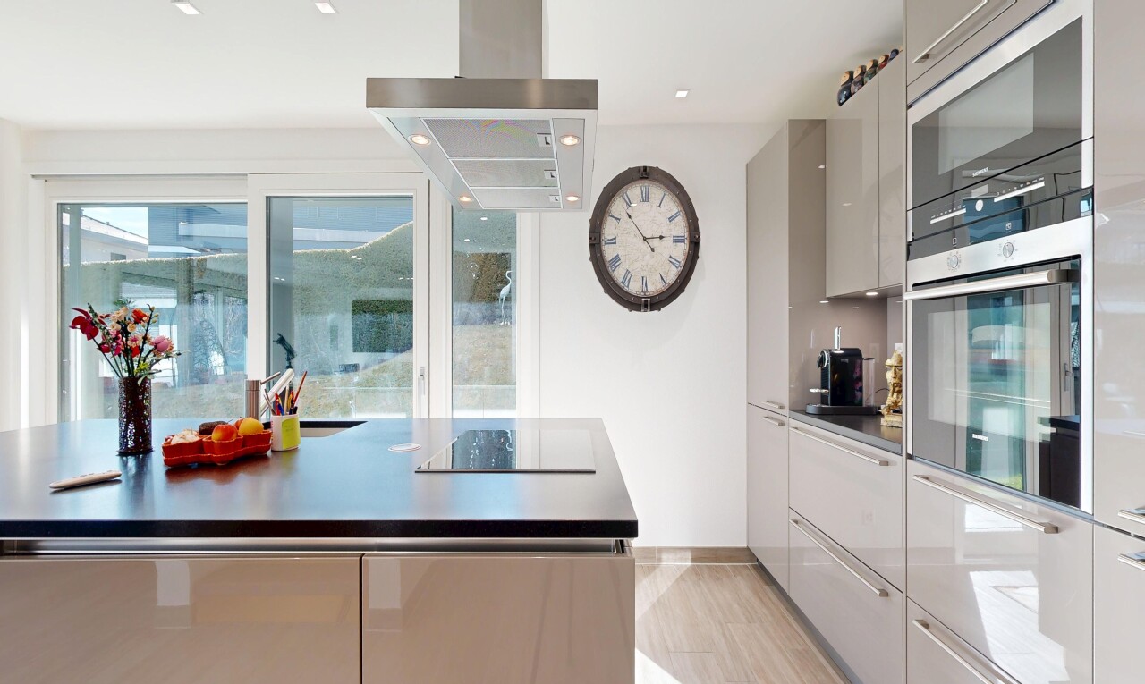 cuisine avec armoires à panneau plat, flat panel cabinets, hotte, light floor, et lumière naturelle
