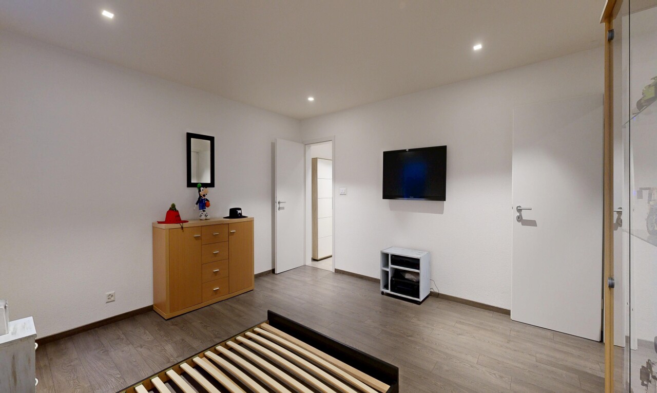 chambre avec télévision, sol en finition bois, wood finish floor, inside property, et cloison sèche
