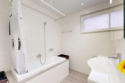 bathroom with tiled shower / bath combo, tile walls, light wood-type flooring, and vanity