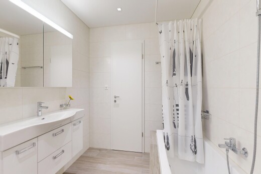 bathroom with tile walls, vanity, light wood-style flooring, and tiled shower / bath