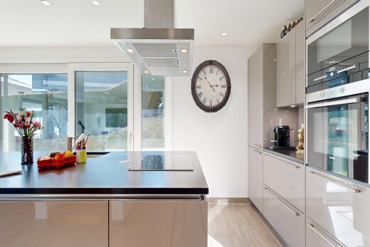 cuisine avec armoires à panneau plat, flat panel cabinets, hotte, light floor, et lumière naturelle