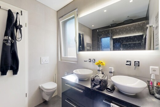 bathroom featuring a towel warmer, double vanity, and a shower