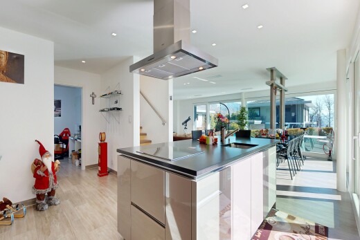 kitchen featuring modern cabinets, island range hood, a center island with sink, light wood-style floors, and dark countertops