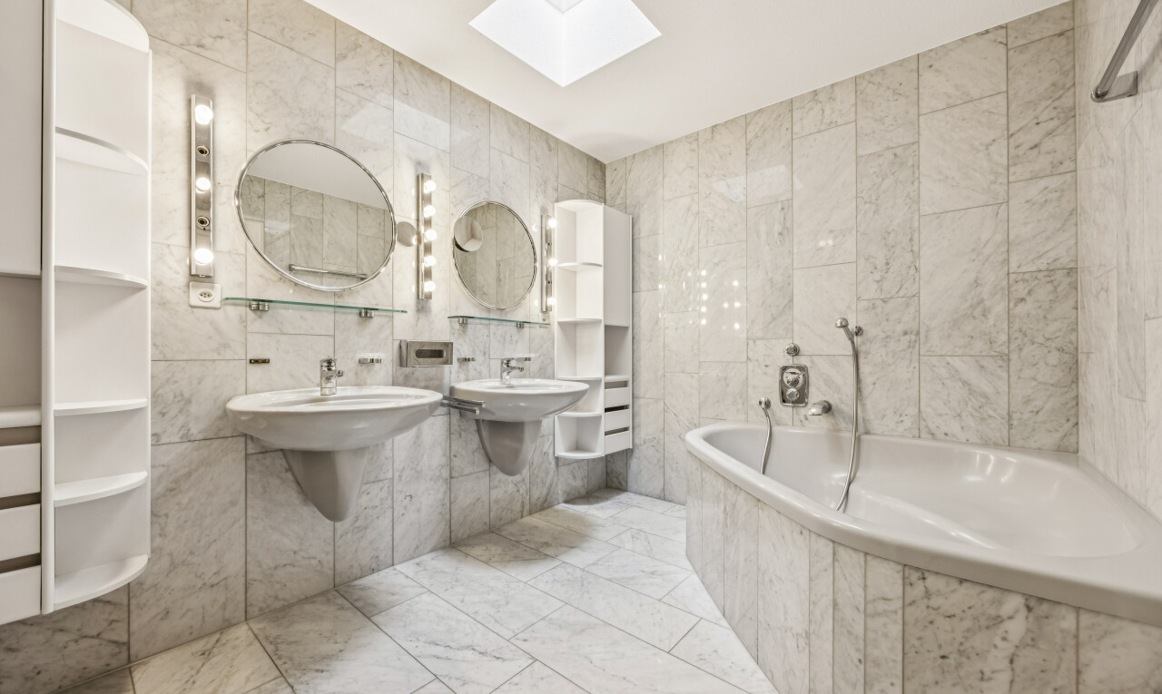 bathroom with tile walls, a garden tub, light marble finish floors, and two sinks