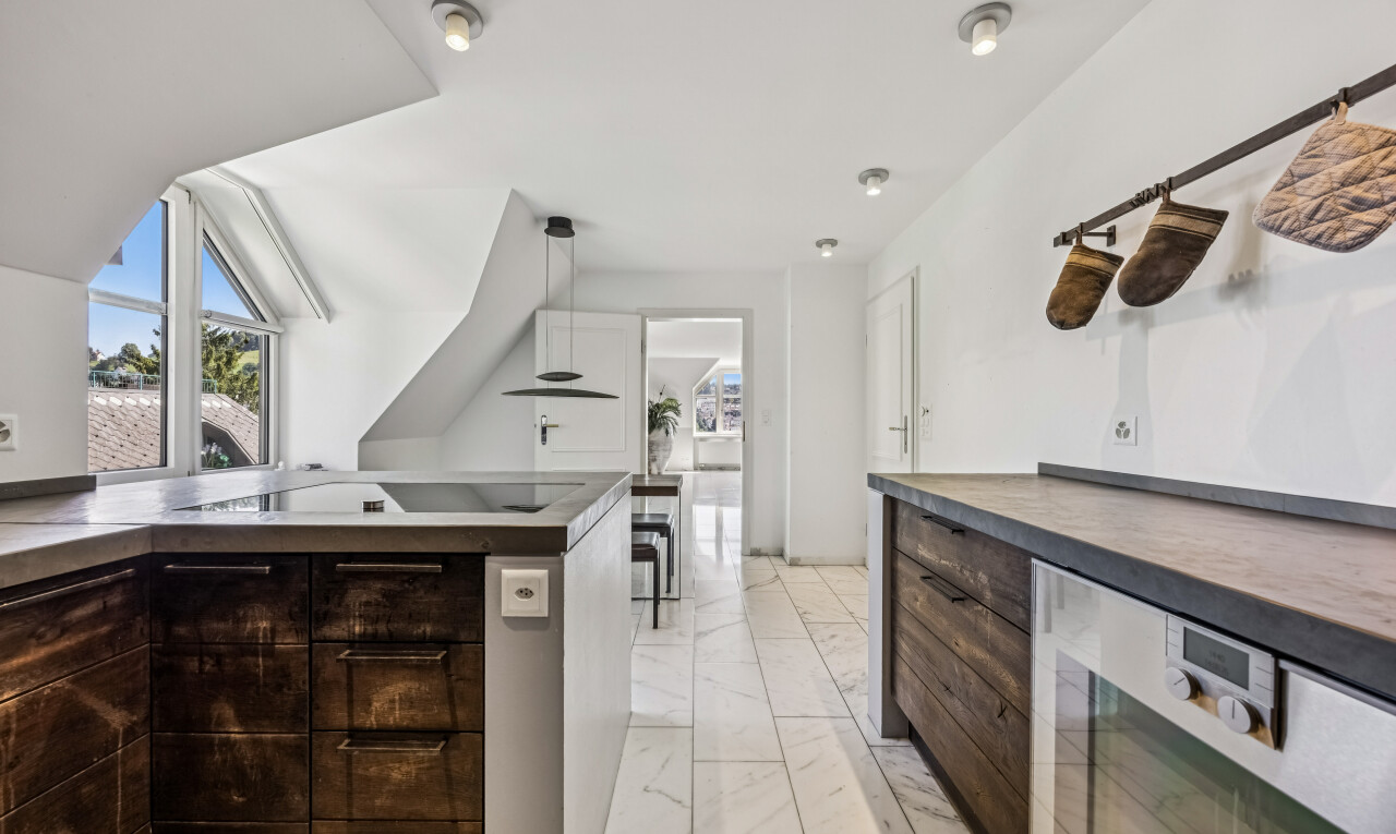 kitchen with dark wood finish cabinetry, healthy amount of natural light, light marble finish floors, and oven