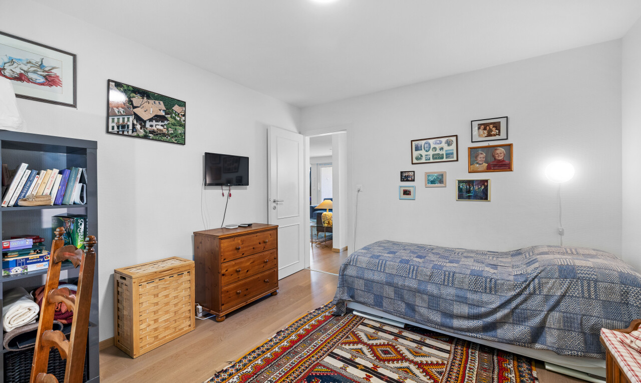 zimmer / schlafzimmer mit fernseher, holzfußboden, wood finish floor, gipskartonwand, und drywall