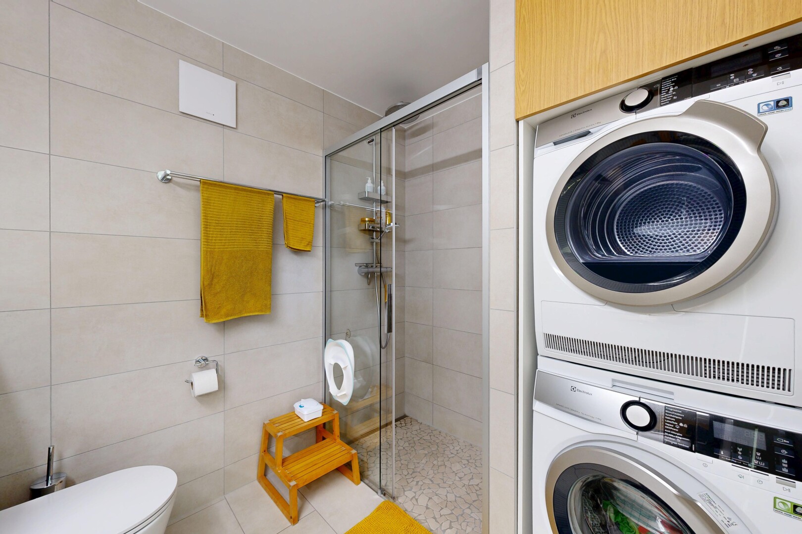 buanderie avec buanderie, lave-linge et sèche-linge superposés, light floor, mur en carrelage, et tile wall