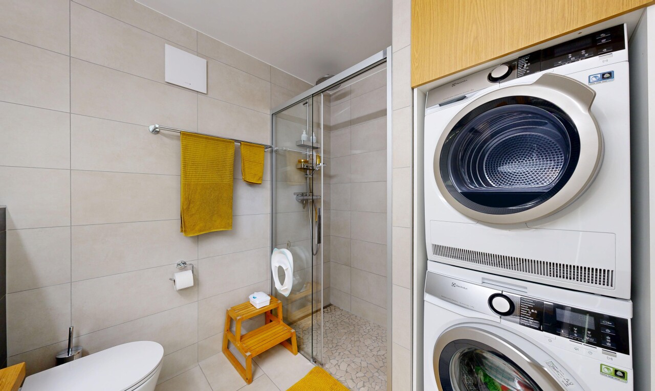 buanderie avec buanderie, lave-linge et sèche-linge superposés, light floor, mur en carrelage, et tile wall