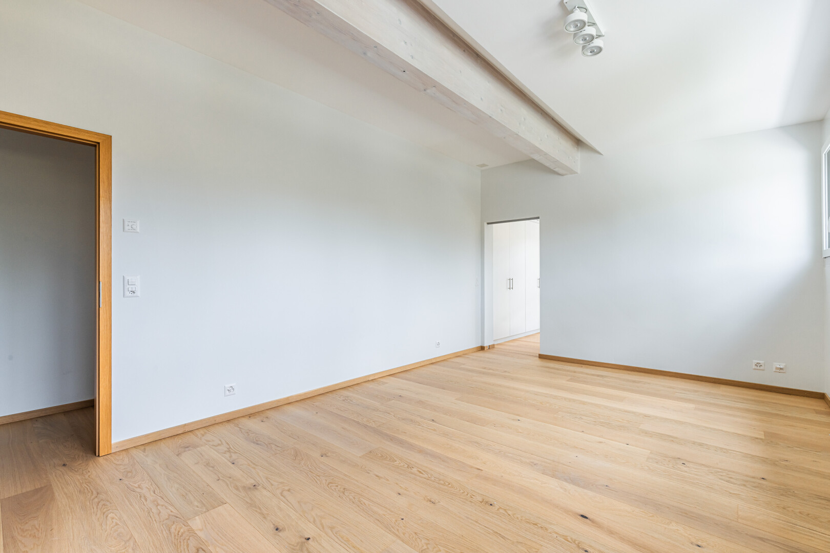 pièce vide avec plafond à poutres, beamed ceiling, light floor, sol en finition bois, et wood finish floor