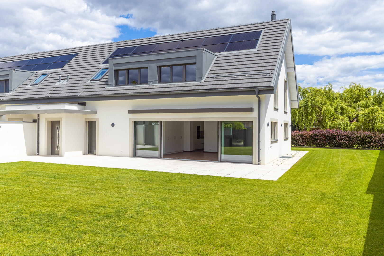 façade avec pelouse, panneaux solaires, property visible, day time, et bardage en stuc