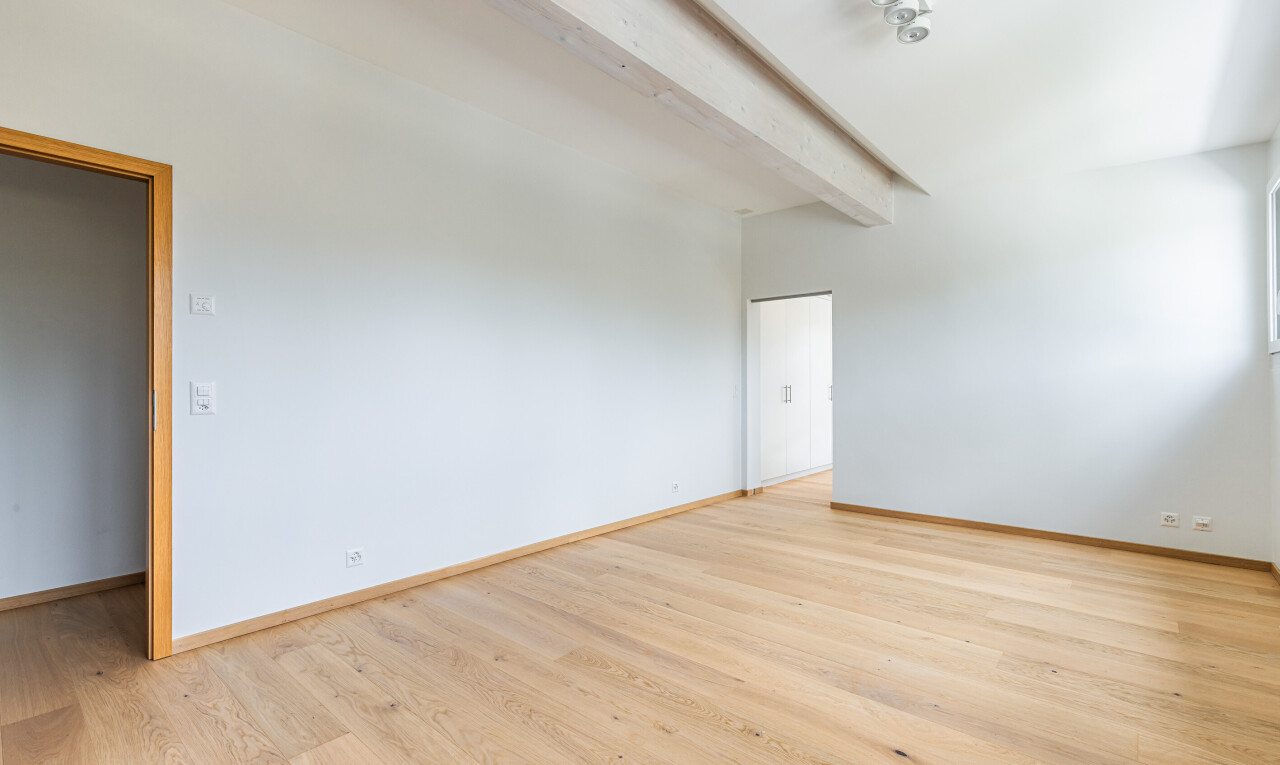 pièce vide avec plafond à poutres, beamed ceiling, light floor, sol en finition bois, et wood finish floor