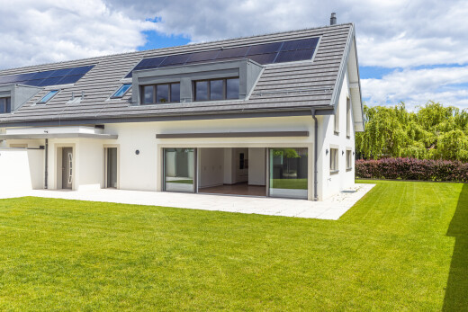 façade avec pelouse, panneaux solaires, property visible, day time, et bardage en stuc