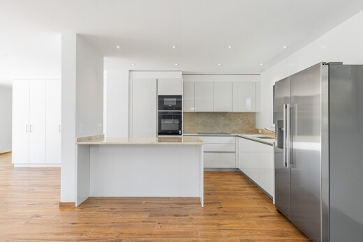cuisine avec flat panel cabinets, armoires à panneau plat, réfrigérateur, light countertops, et sol en finition bois