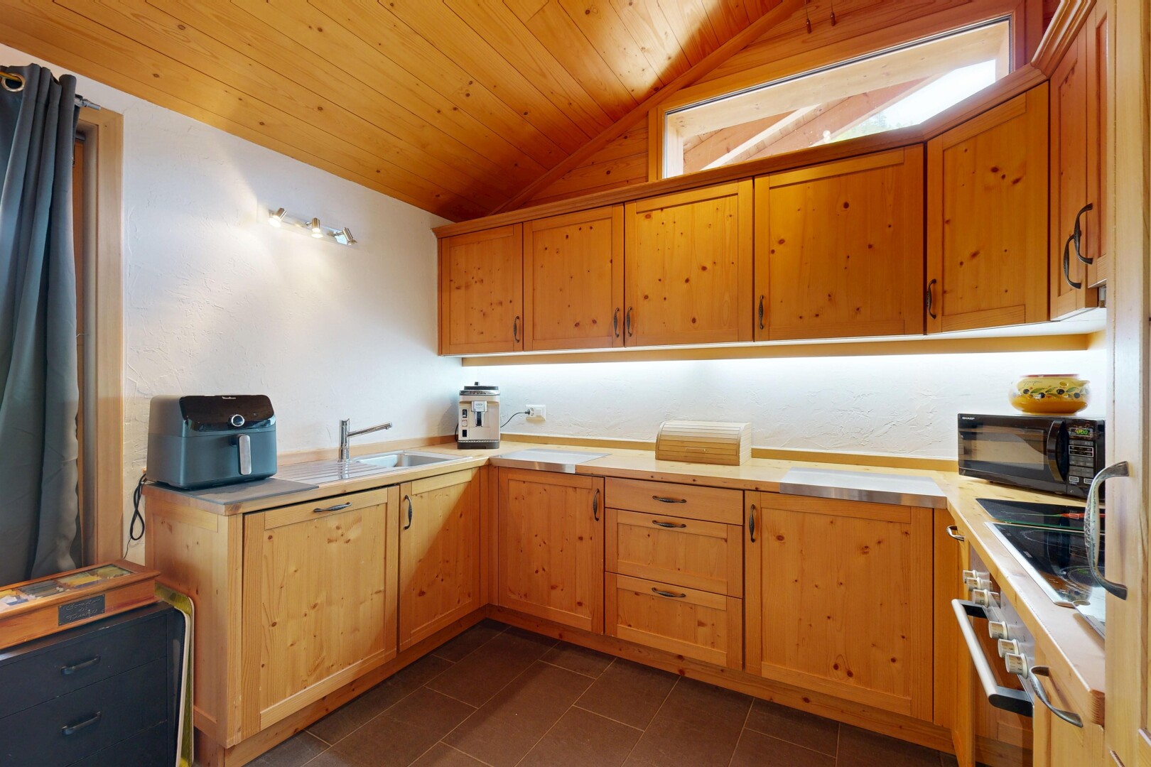 cuisine avec plafond en bois, wood ceiling, armoires avec moulures, crown molding cabinets, et plans de travail