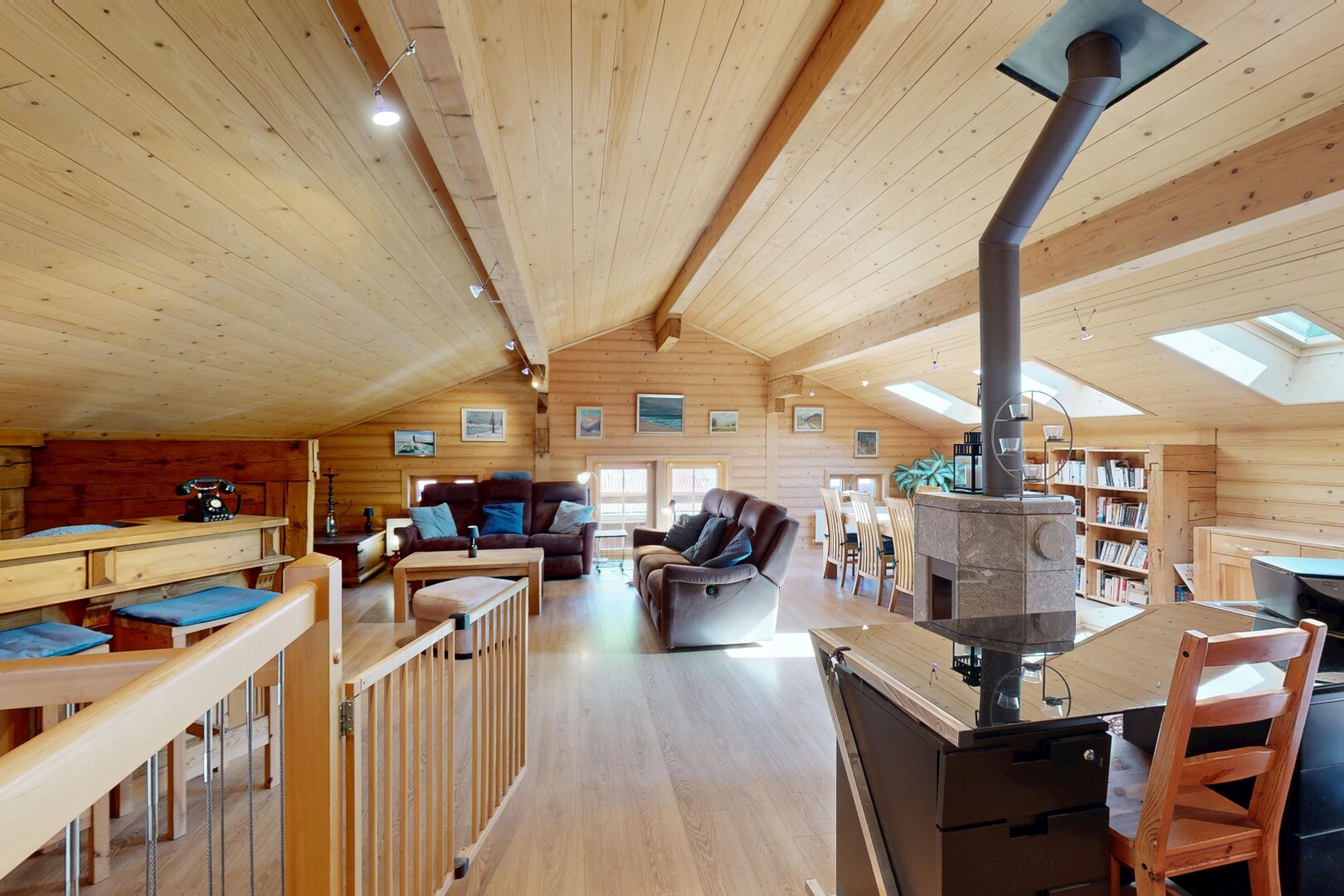 salon / salle à manger avec poêle à bois, sol en finition bois, wood finish floor, inside property, et mur en bois