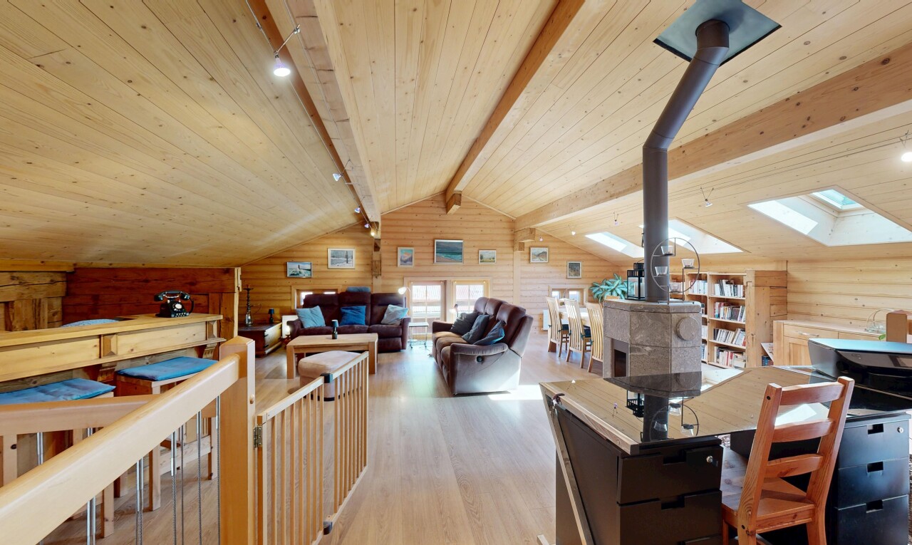 salon / salle à manger avec poêle à bois, sol en finition bois, wood finish floor, inside property, et mur en bois