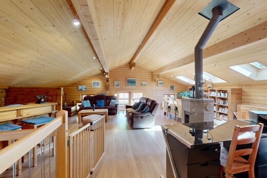 salon / salle à manger avec poêle à bois, sol en finition bois, wood finish floor, inside property, et mur en bois