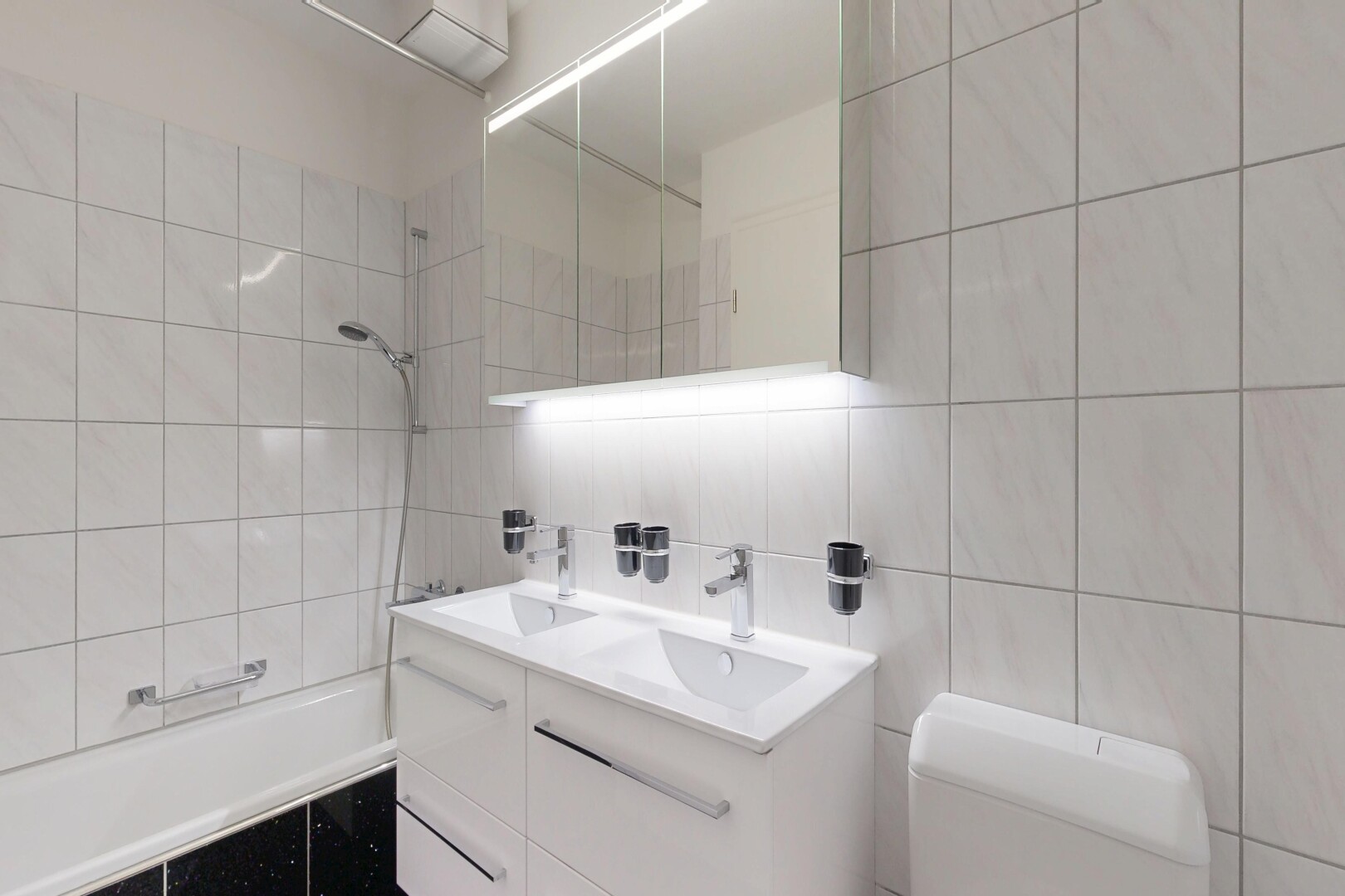 bathroom with double vanity, tiled shower / bath combo, tile walls, and backsplash