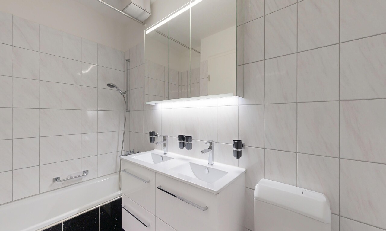 bathroom with double vanity, tiled shower / bath combo, tile walls, and backsplash